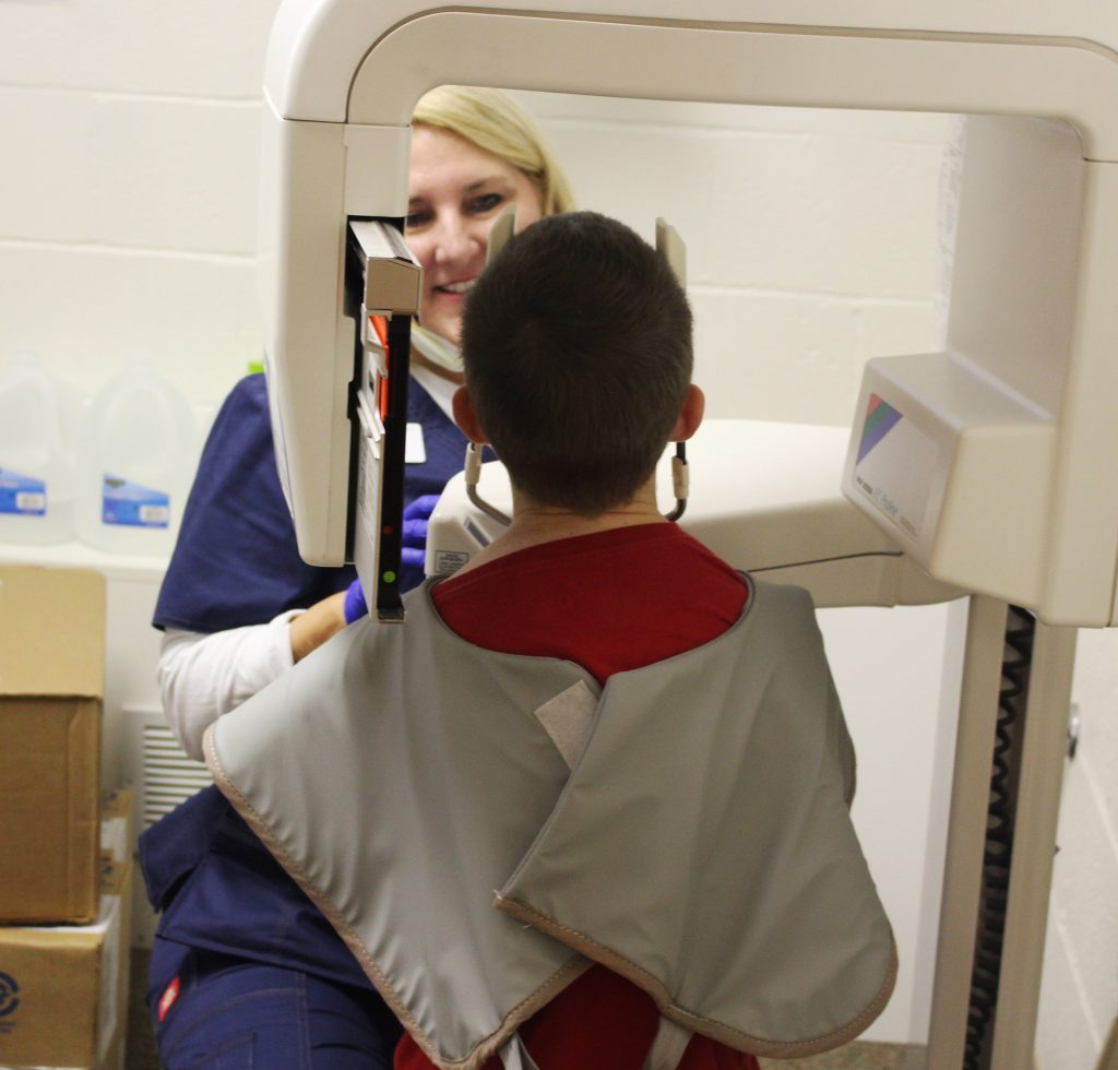 Dental assistant performing dental x-ray on child
