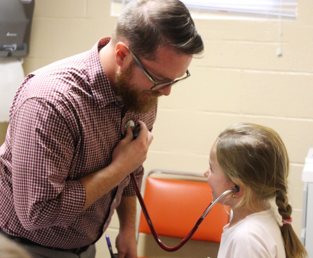 Child listening to nurse's heartbeat with stethoscope